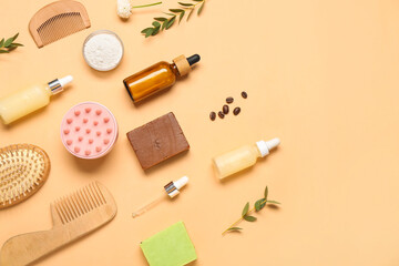 Hair scalp massager with shampoo bars, bottles of cosmetic products and brushes on beige background