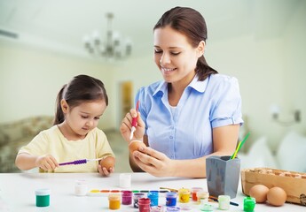 Easter Family.Young mother teaching happy little kid to dye and decorate eggs with paints for Easter holidays