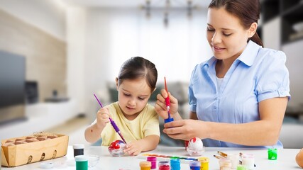 Easter Family.Young mother teaching happy little kid to dye and decorate eggs with paints for Easter holidays