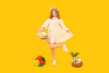 Beautiful young woman in bunny ears with Easter baskets, carrot-shaped toys and flowers on yellow background