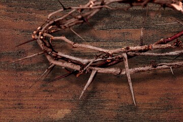 Christ a crown of thorns, on a rustic wooden surface next to a rusty nail