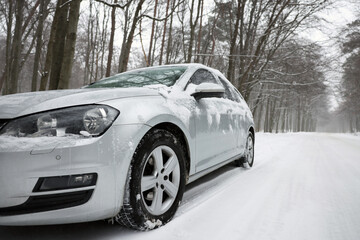 Car with winter tires on snowy road in forest, space for text