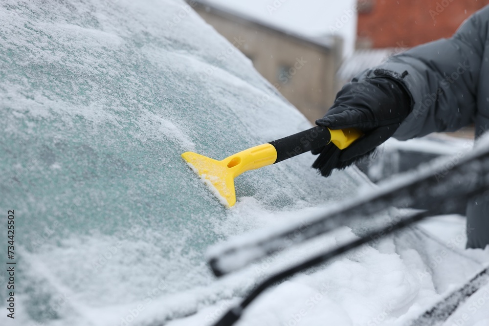 Wall mural man cleaning snow from car windshield outdoors, closeup