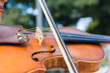 closeup of violin bow on strings outdoors,