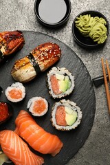 Set of delicious sushi rolls on dark grey table, flat lay
