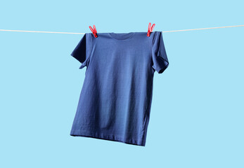 T-shirt drying on washing line against light blue background