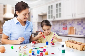 Easter Family concept. Loving young mother teaching happy little kid decorate eggs with paints for Easter.