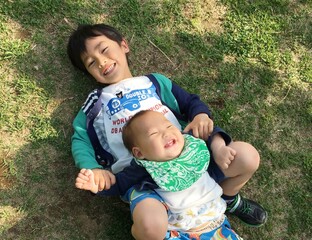芝生に寝転ぶ日本人の子供の兄弟