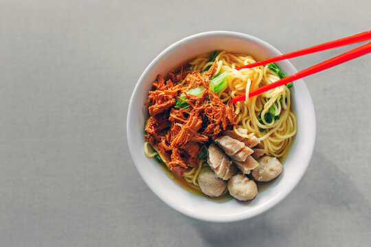 Indonesian famous street food Mie Ayam or chicken noodles served with meatballs, vegetables 