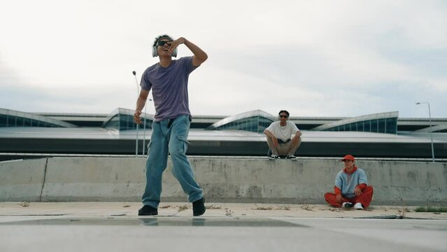 Group of asian break dancer perform street dance with multicultural friend support and moving hip hop music. Attractive handsome hipster practice b boy dance at street. Outdoor sport 2024. Sprightly.