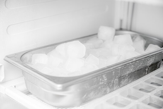 Frozen ice cubes in a stainless steel bowl in the freezer.