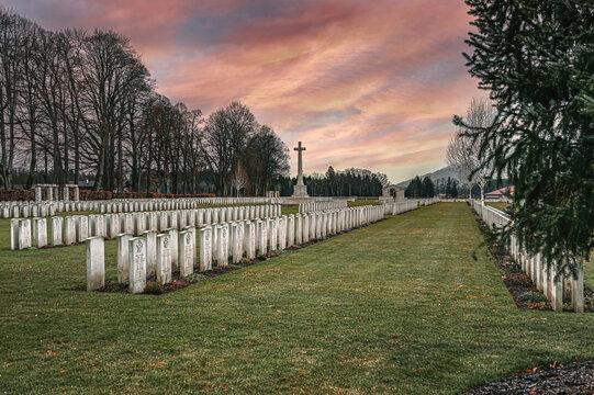 A European cemetery with marble tombstones against a bleak red sky.