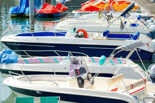 Moored yachts and boats at the pier for walks on rivers, seas and lakes. Water tourist transport.