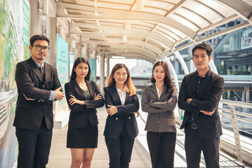 Portrait Group of businesspeople arms crossed smiling look at camera in modern city background. Happy Businessman, businesswoman teams partnership. Business people teams positive teamwork standing.