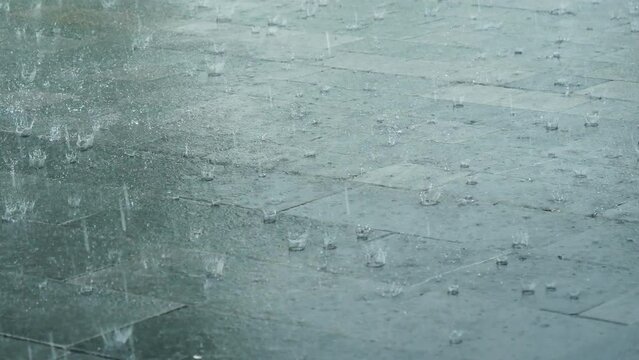 Heavy rainy in raining season weather during thunderstorm raindrops splash on water surface. Blurred background while falling rain shower windy outdoors. Climate change motion raindrops splash
