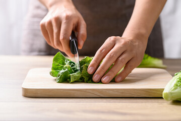 Organic cos romaine lettuce cutting on wooden board, Food ingredient for healthy salad - obrazy, fototapety, plakaty