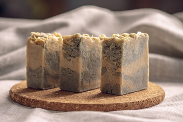 Pieces of craft natural soap on a round cork stand and cotton fabric