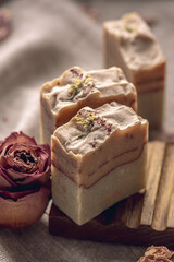 Delicate pieces of natural floral soap made from safe, eco friendly organic ingredients in a wooden soap dish. A beautiful postcard