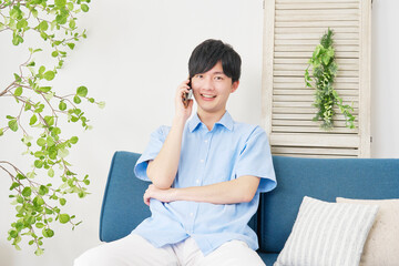 リビングでスマートフォンで電話をする男性　カメラ目線