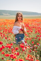 Obraz na płótnie Canvas Woman poppies field. Side view of a happy woman with long hair in a poppy field and enjoying the beauty of nature in a warm summer day.