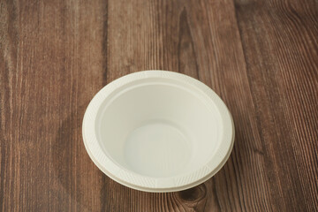 White plastic plate made of plastic on a wooden background