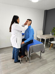 Latin woman doctor medical specialist checks dark-skinned male patient suffering from headache due to injury or stress