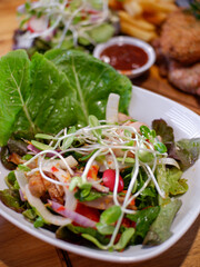 Tasty healthy vegetables salad with micro greens on wooden table.