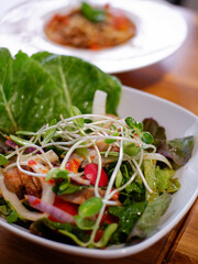 Tasty healthy vegetables salad with micro greens on wooden table.