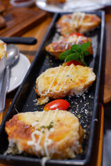 Slices of toasted bread with garlic, cheese and herbs on wooden table. Toned with color filter and soft noise to get old camera effect. Soft focus and blurred. 