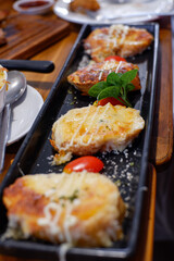 Slices of toasted bread with garlic, cheese and herbs on wooden table. Toned with color filter and soft noise to get old camera effect. Soft focus and blurred.