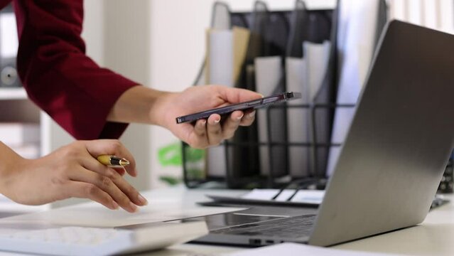 2FA login concept. Businesswoman working on laptop logging in on smartphone and modern device. Businesswoman doing paperwork in the office.