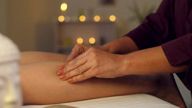 Leg massage in an Ayurvedic massage center - calf muscle  wellness center  aromatherapy  ayurvedic therapy  bokeh  dry massage . A professional massage therapist massages a woman's leg in a spa cen...