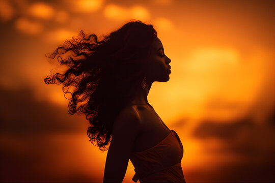 A photograph of a powerful woman standing against a golden sunset backdrop, capturing her strength and determination.