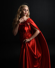 Close up portrait of beautiful blonde model wearing flowing red silk toga gown and crown, dressed...