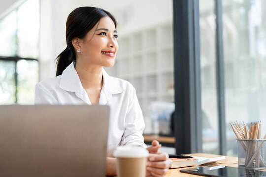 Closeup immage of young beautiful joyful woman smiling while working with laptop in office