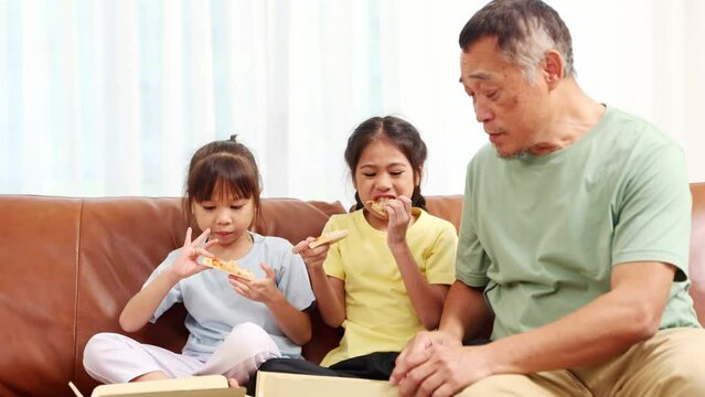 Pizza party at home : Kind hearted grandfather who loves his two granddaughters prepares order seafood flavored pizza delivered to their home fastfood for lunch or snack for the girl happily eat.