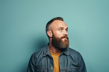Obraz premium Portrait of a bearded man in a denim jacket on a blue background.