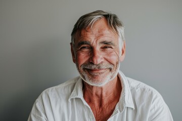 Portrait of a senior man with grey hair and beard smiling at the camera