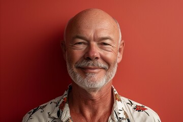 Portrait of a smiling senior man on a red studio background.