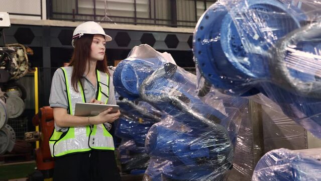 Female engineer walking around carefully inspecting the new robot zone in the warehouse robot is covered clear dustproof plastic sealed and the robot inspection service is waiting electrical testing.