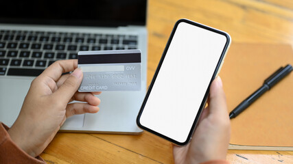 Closeup view female hands holding smartphone with blank empty display and credit card