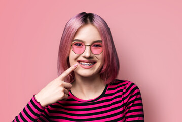 Dental dent care ad concept image - pink haired funny young woman girl in metal braces wear...