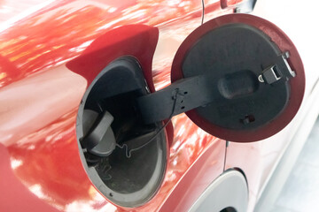 Close up view of the fuel tank cap cover on the red car. Open petrol cap cover.