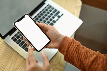 Woman hands using mobile phone at working desk. Empty screen for advertising and creative design
