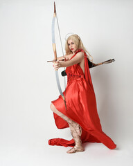 Full length portrait of  blonde model dressed as mythological fantasy goddess in flowing red silk...