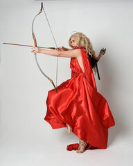Full length portrait of  blonde model dressed as mythological fantasy goddess in flowing red silk...
