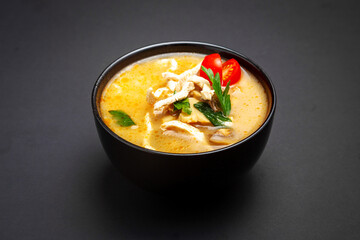 Tom yum soup with chicken. On a black background.