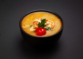 Tom yum soup with shrimp. On a black background.