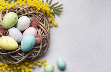 Colorful Easter Eggs Nestled in a Wicker Basket With Yellow Flowers on a Light Background