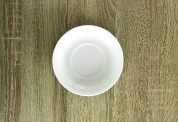 Empty white plate on wooden table, view from above. Image with copy space. Top view with copy space.